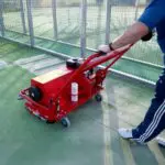 SMG TurfSoft TS2 artificial turf cleaner being operated on a green tennis court, clearing and cleaning the surface effectively.