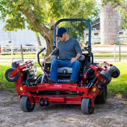 A man operates a red Toro zero-turn mower in a grassy area, showcasing its features and design