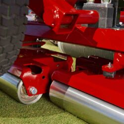 Close-up of the Toro GreensPro 1260's hydraulically driven drive roller and robust red chassis on turf