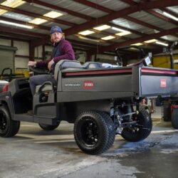A man operates a Toro utility vehicle in a warehouse, showcasing its design and features