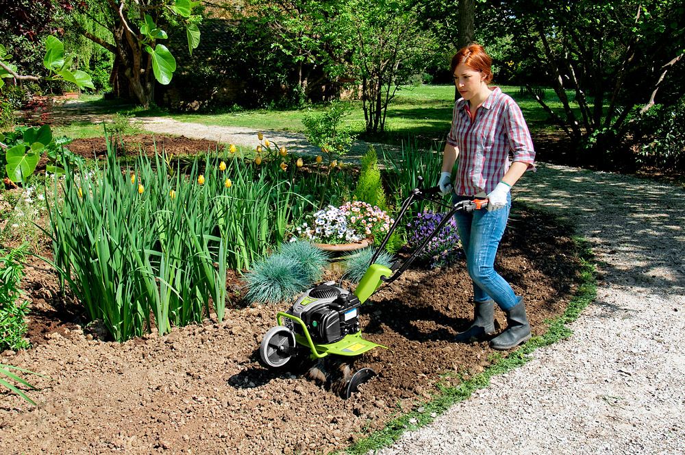 Woman pushing Grillo GZ1 Rotary Tiller on a sunny day in a residential flower garden block