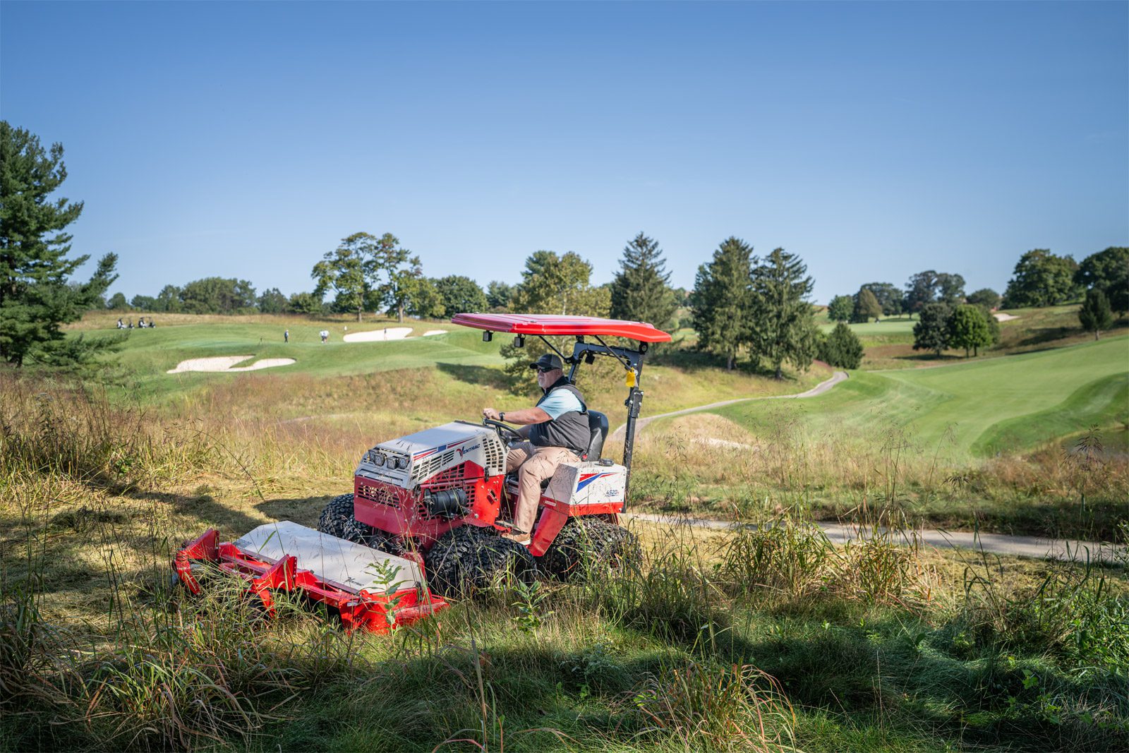 A Ventrac machine mows grass on a golf course, showcasing its low profile and versatility on slopes