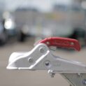 Close-up of a red coupling handle on a low-deck trailer designed for transporting golf carts