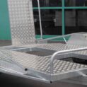 Low-deck trailer with a textured surface, light ramp, and mag wheels for transporting golf carts