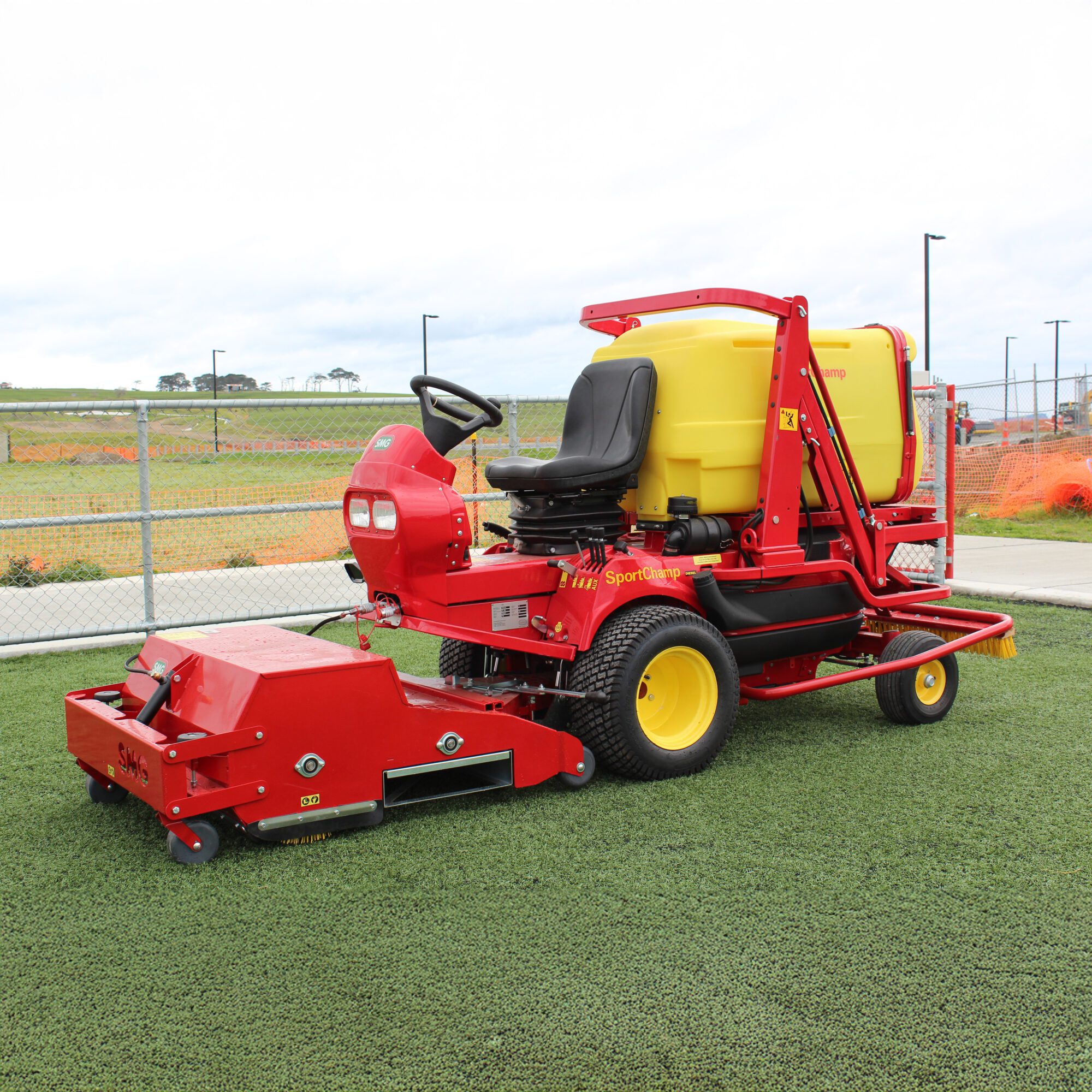 SMG SportChamp SC2D ride-on turf maintenance machine artificial field SMG SportChamp SC2D ride-on artificial turf cleaner parked on a synthetic field.