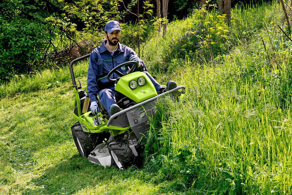Mower cutting long grass on property
