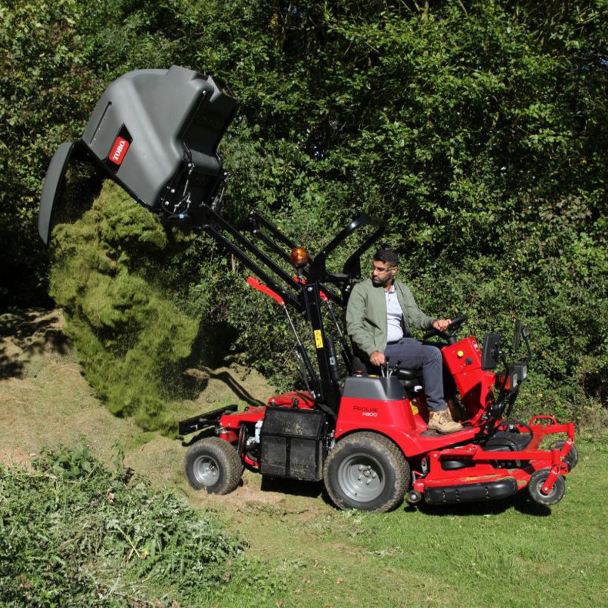 Pro Line H800 31051 Action 2 Red Toro ride-on mower in action, collecting grass clippings with high-lift hopper and operator seated