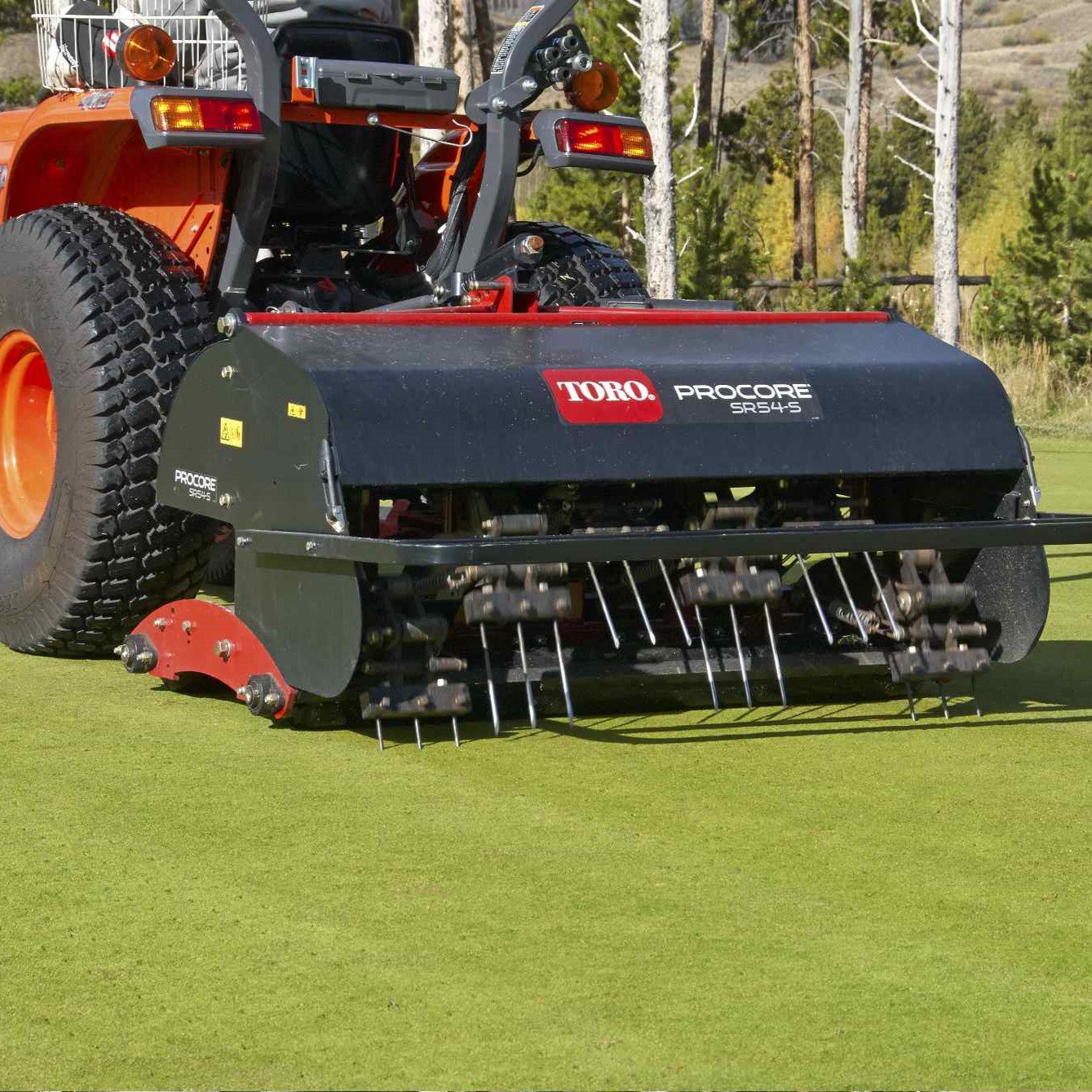 ProCore-TORO-Two-Behind-sq-2 A Toro turf aerator attached to a tractor, featuring deep-tine heads and a hydraulic top link on grass