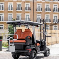 Rear view of a sleek black golf cart with orange seats, showcasing its stylish design and spacious seating
