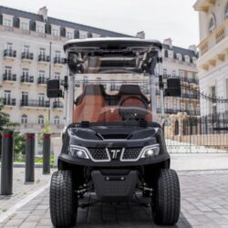 Front view of a sleek black golf cart with orange seats, showcasing its modern design and sturdy tires