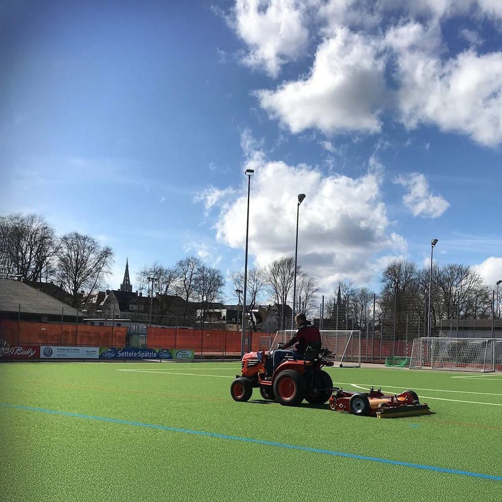 SMG TurfCare TCA1400 soccer field turf cleaning with tractor Tractor towing SMG TurfCare TCA1400 turf cleaner on a synthetic soccer field for field maintenance.