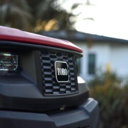 Close-up of the front grille of a red Toro utility vehicle with blurred background