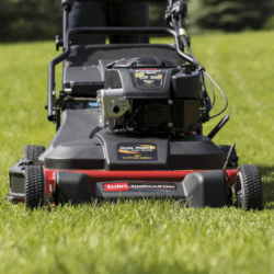 A close-up of a Toro lawn mower cutting grass, showcasing its engine and wide cutting deck