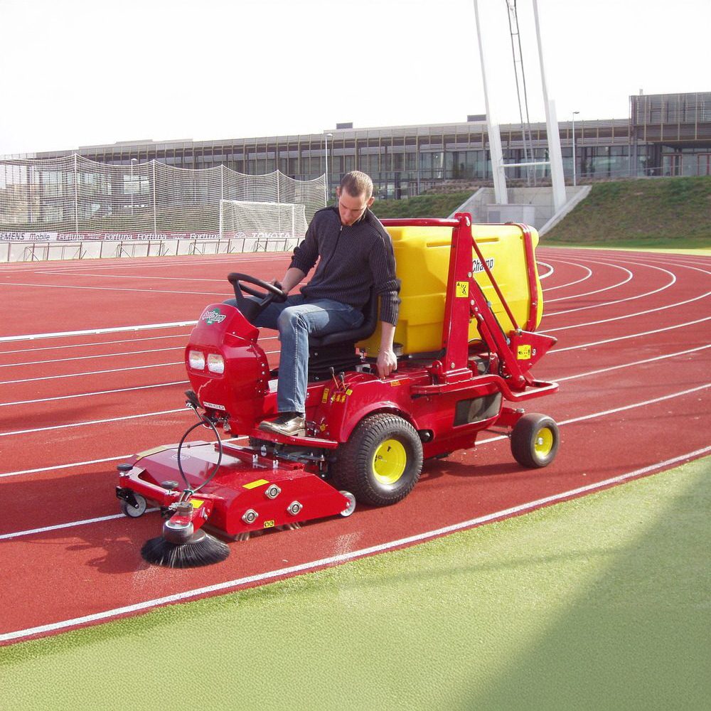 SMG SportChamp SC2D artificial turf cleaner ride-on track maintenance SMG SportChamp SC2D ride-on machine cleaning an athletic track at a sports facility.