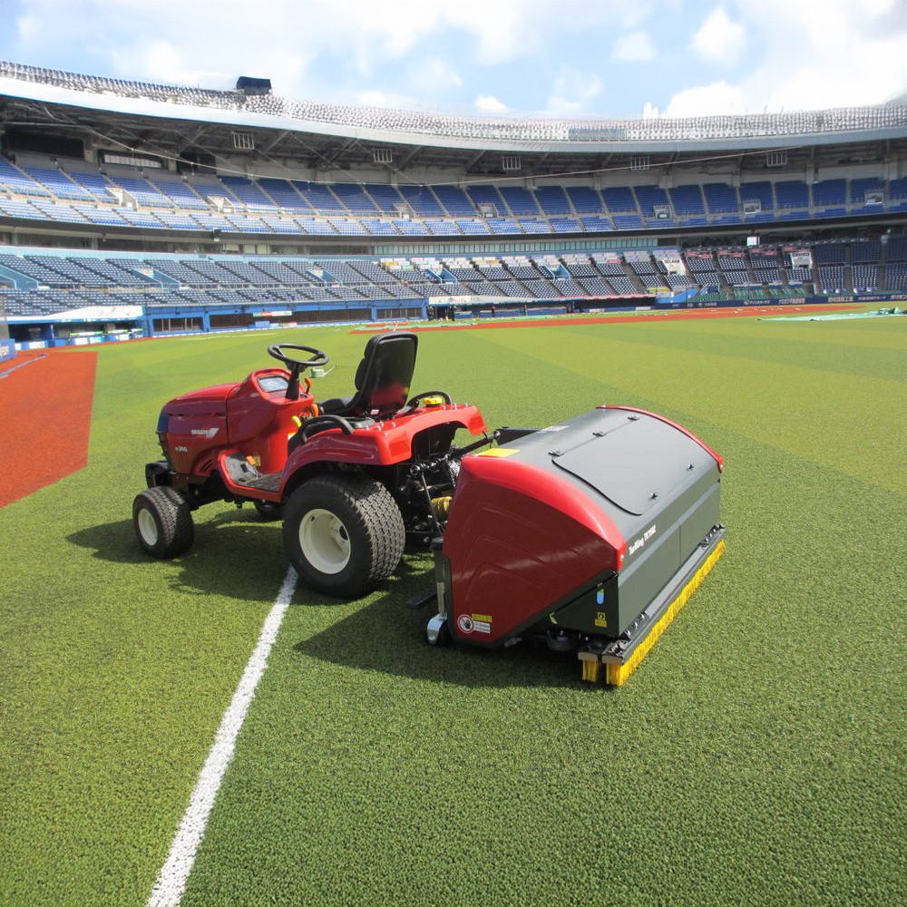 SMG TurfKing TK1502 turf cleaner tractor attachment football stadium maintenance SMG TurfKing TK1502 turf cleaner attached to a red tractor maintaining artificial turf at a large football stadium.