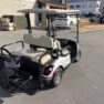 Silver 2015 Yamaha golf cart with beige seats, rear storage, parked on pavement in good condition