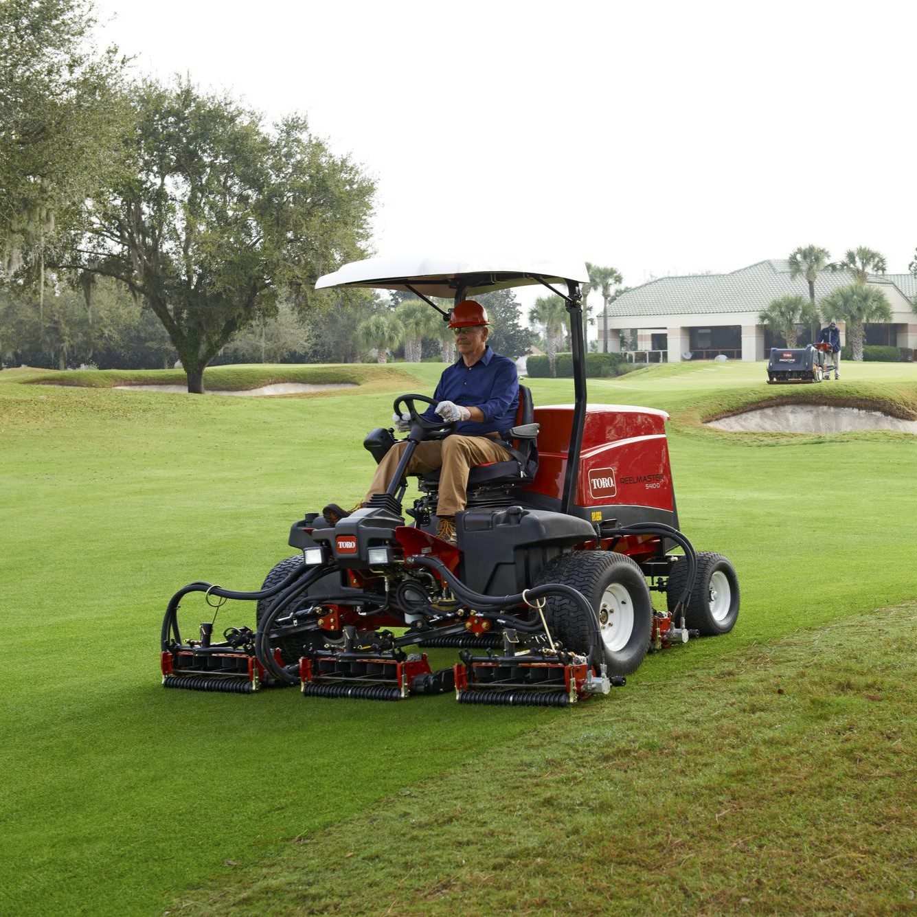 cm2373s_rm5410d_teir_4_loc_fl_35 sq Red ride-on mower with a driver, cutting grass on a golf course, showcasing precision cutting units