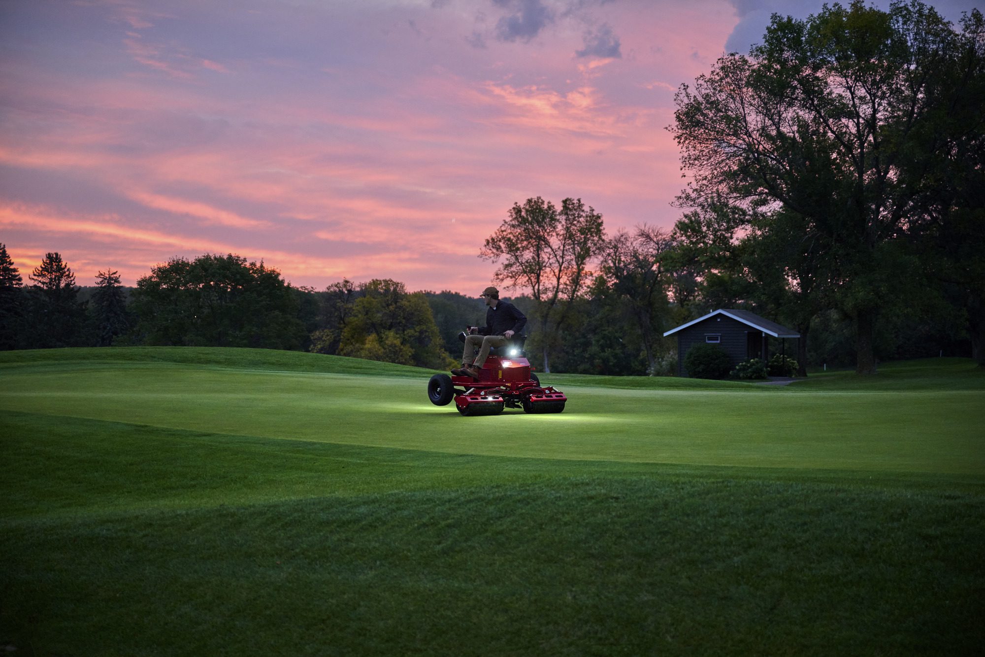 cm25_6197L_GreensPro_e1700_049 A person operates an electric greens roller on a golf course at sunset, highlighting its performance and design