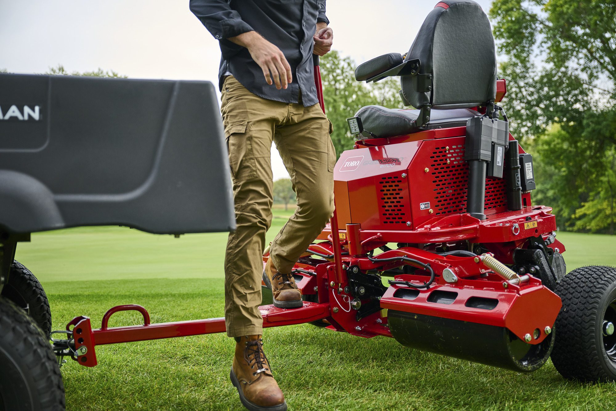 cm25_6197L_GreensPro_e1700_233 A person operates a red electric greens roller on a grassy field, showcasing its design and features
