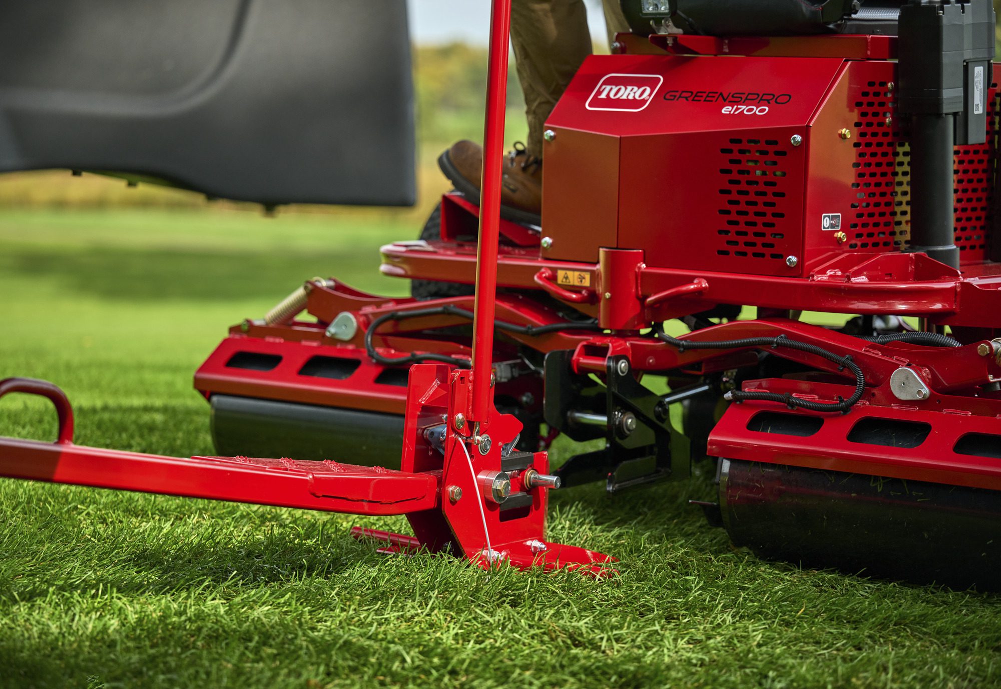 cm25_6197L_GreensPro_e1700_280 Close-up of the red electric greens roller's SmartHitch and roller components on green grass