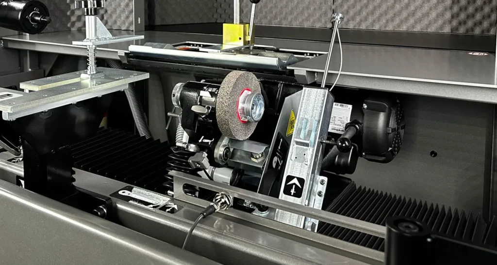 Close-up of a reel grinder's motor and grinding wheel inside a protective enclosure
