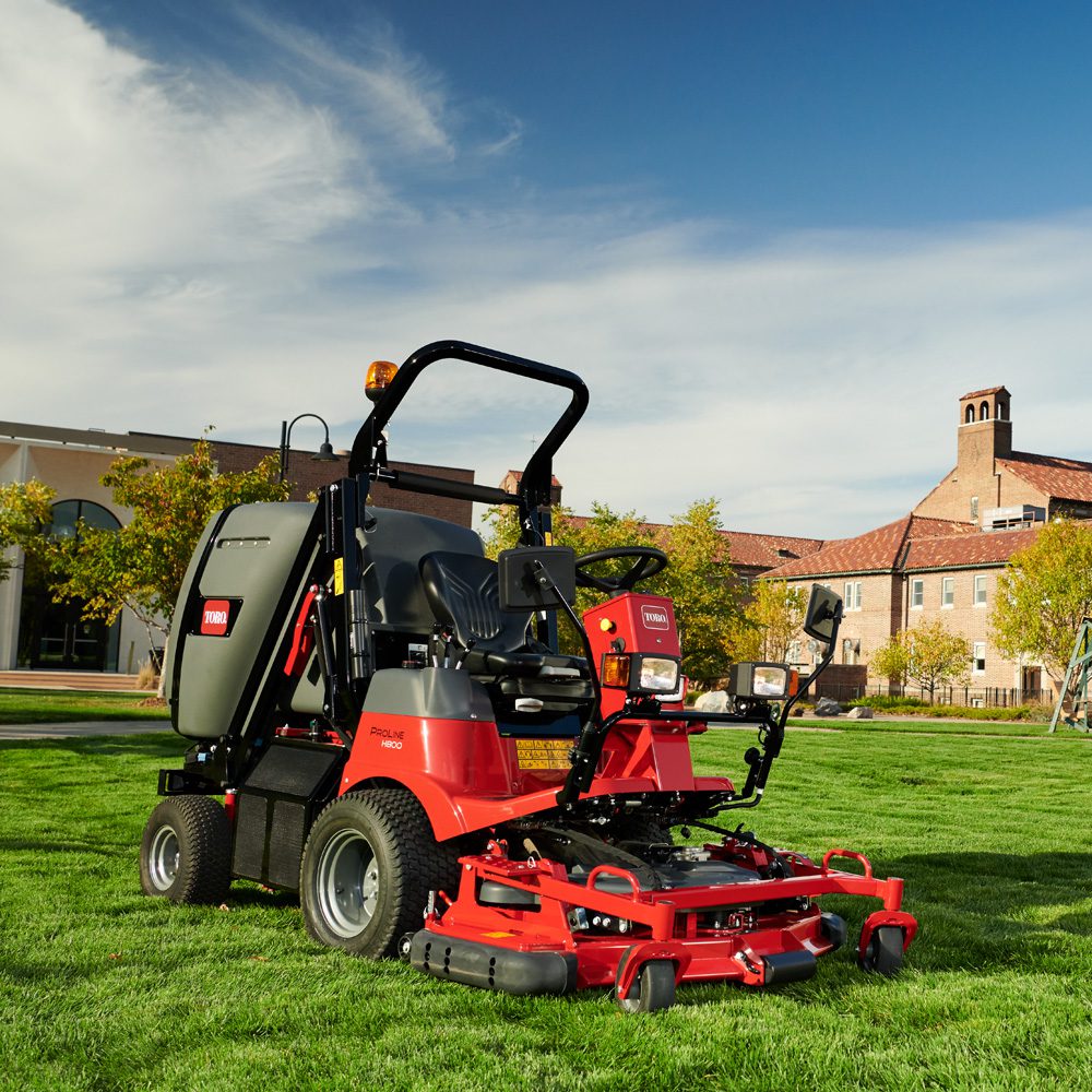 h800gallery1 Red Toro ride-on mower on green grass, showcasing its out-front deck and high-lift collection system
