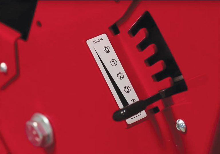 Close-up of a red control panel with a gauge and lever for adjusting settings on the tractor