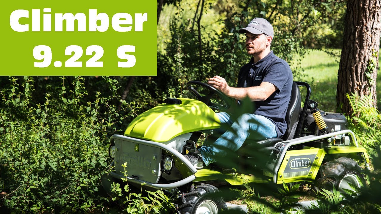 A man operates a bright green Grillo Climber mower in dense grass and foliage